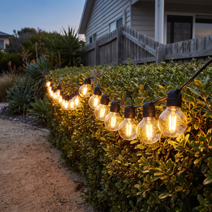Warm White Solar Festoon Christmas String Lights – 17m, 15 Bulbs – glowing along a coastal garden path at twilight