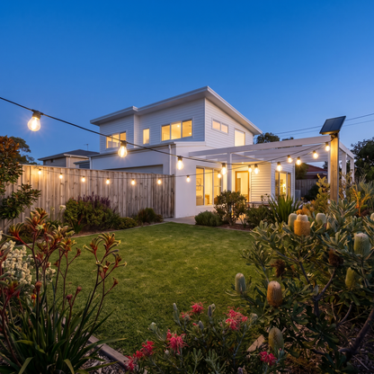 Warm White Solar Festoon Christmas String Lights – 17m, 15 Bulbs – strung across the front yard of a modern home at dusk